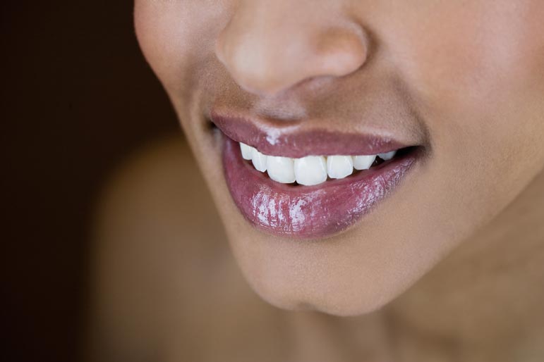 a dark-skinned woman smiles showing off her white teeth