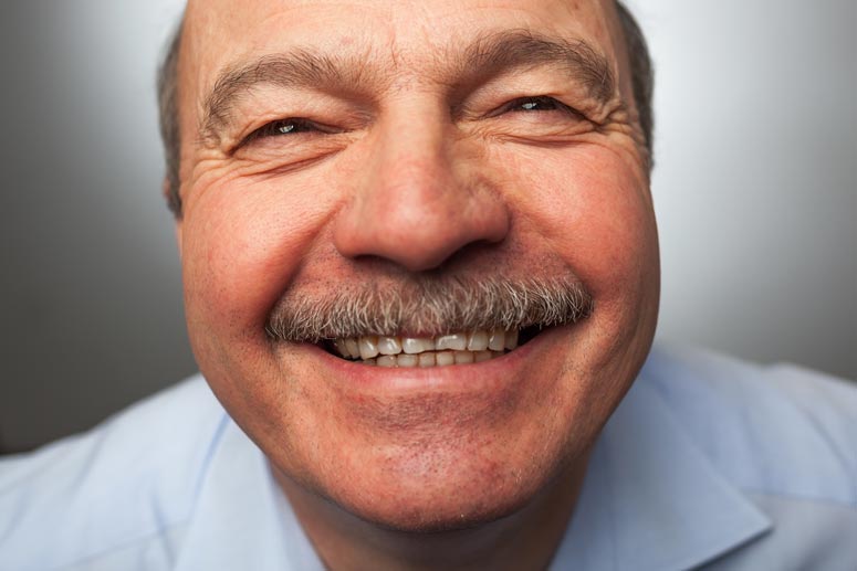 an old man wearing a blue shirt and smiling up at the camera