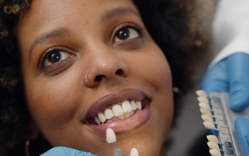 woman having teeth color-matched to porcelain veneer color samples